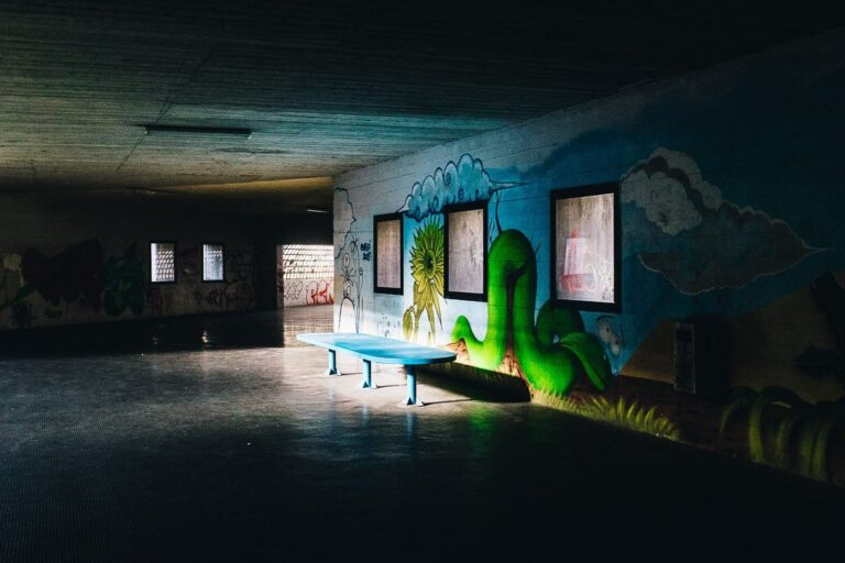 Stanza abbandonata con graffiti colorati e tavolo da ping pong in cemento.