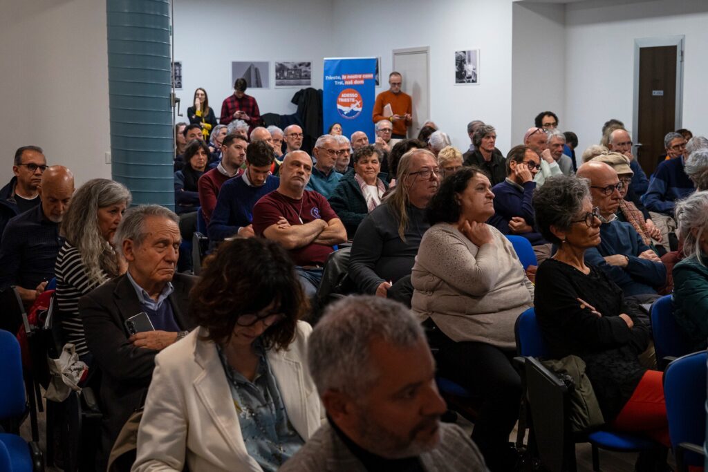 Assemblea pubblica affollata con cittadini attenti in sala riunioni