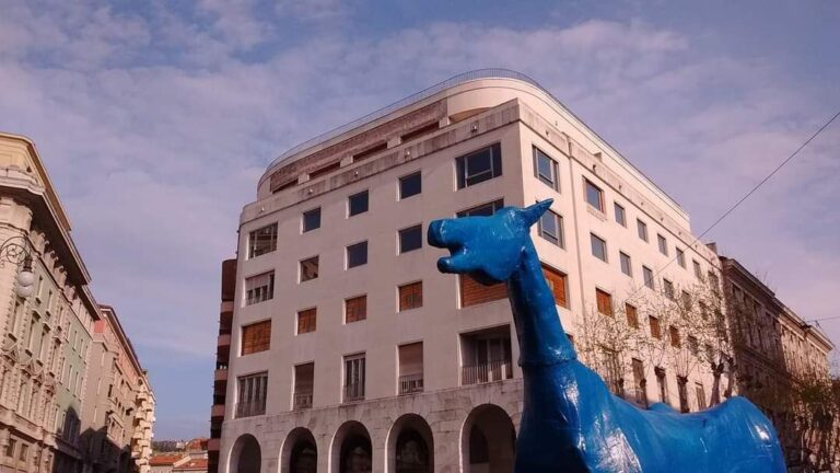 Scultura di cavallo blu in piazza storica europea con edifici eleganti.
