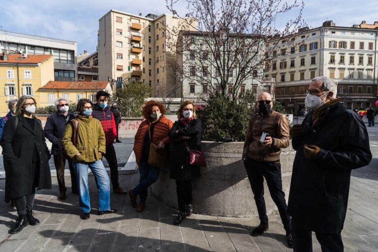 Gruppo in piazza cittadina d’inverno, con mascherine e cappotti, durante un incontro all’aperto.