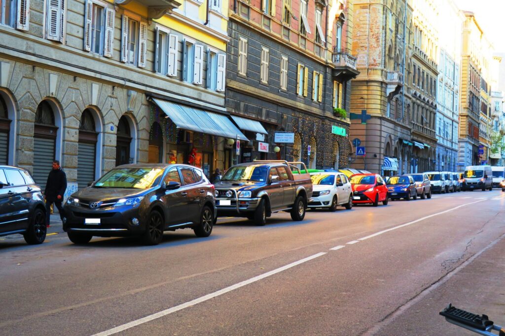 Traffico urbano a Trieste tra palazzi storici e auto in coda.