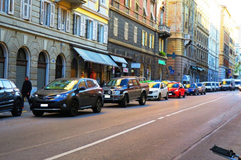 Traffico urbano a Trieste tra palazzi storici e auto in coda.