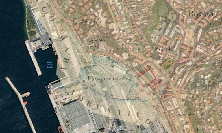 Vista aerea di porto costiero e città compatta con moli e tetti rossi.