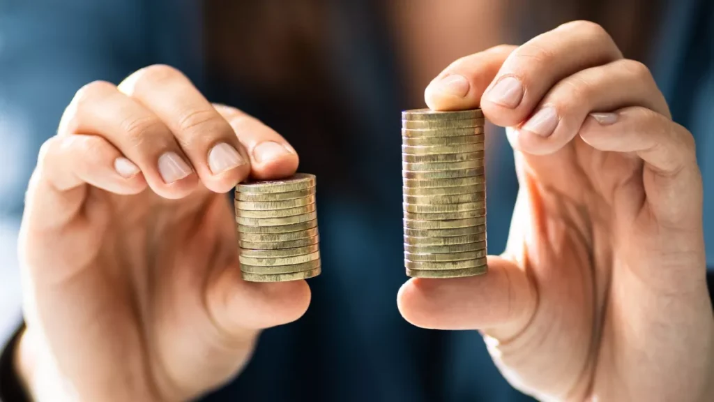 Mani con pile di monete diverse, simbolo di risparmio e crescita finanziaria