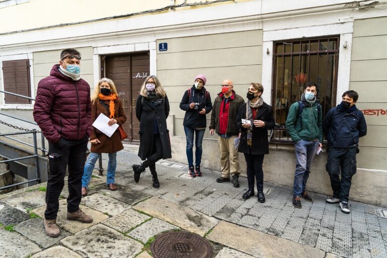 Gruppo con mascherina davanti a edificio storico in pietra.