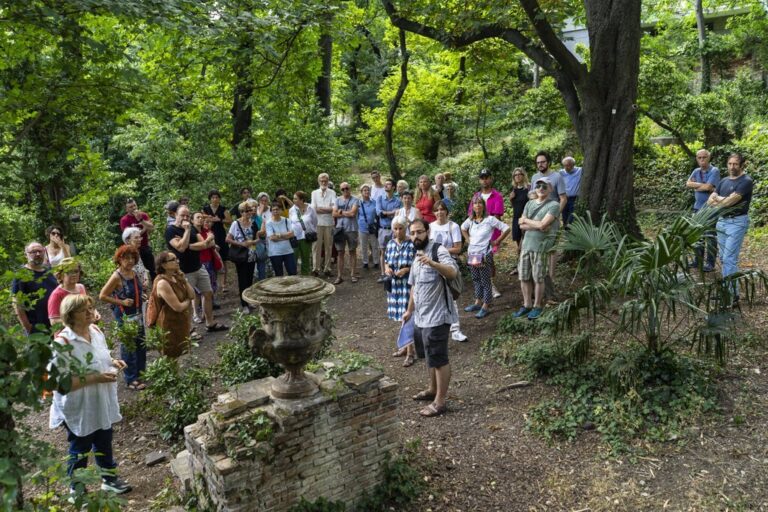 Visita guidata tra rovine nel bosco, con gruppo di turisti e guida.