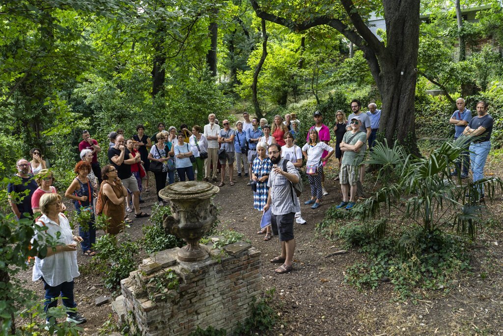 Visita guidata tra rovine nel bosco, con gruppo di turisti e guida.