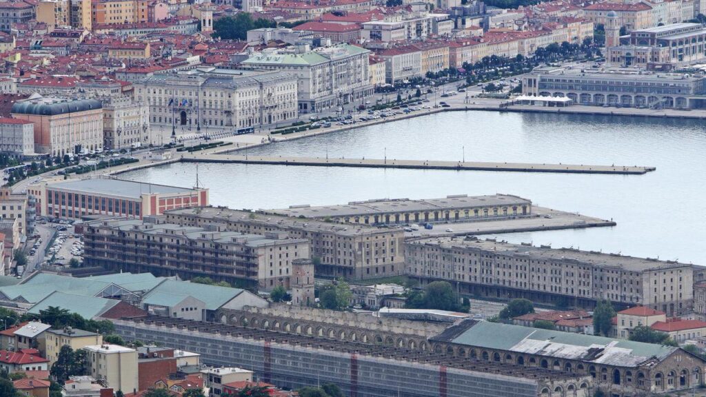 Veduta aerea di porto storico, moli rettilinei e città europea sul mare.