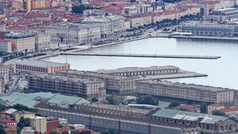 Veduta aerea di porto storico, moli rettilinei e città europea sul mare.