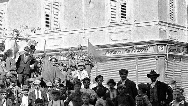Folla storica davanti alla Manifattura di San Giacomo, con uomini e ragazzi in strada.