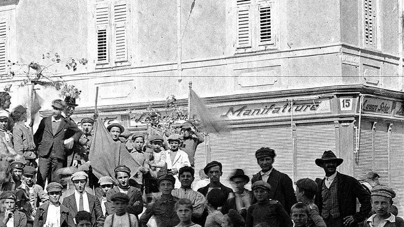 Folla storica davanti alla Manifattura di San Giacomo, con uomini e ragazzi in strada.