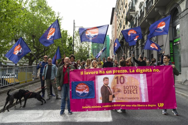 Manifestazione sindacale con striscione rosa contro i salari sotto 5 euro.