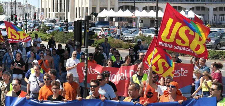 Corteo sindacale USB in piazza cittadina con bandiere rosse e striscione blu.