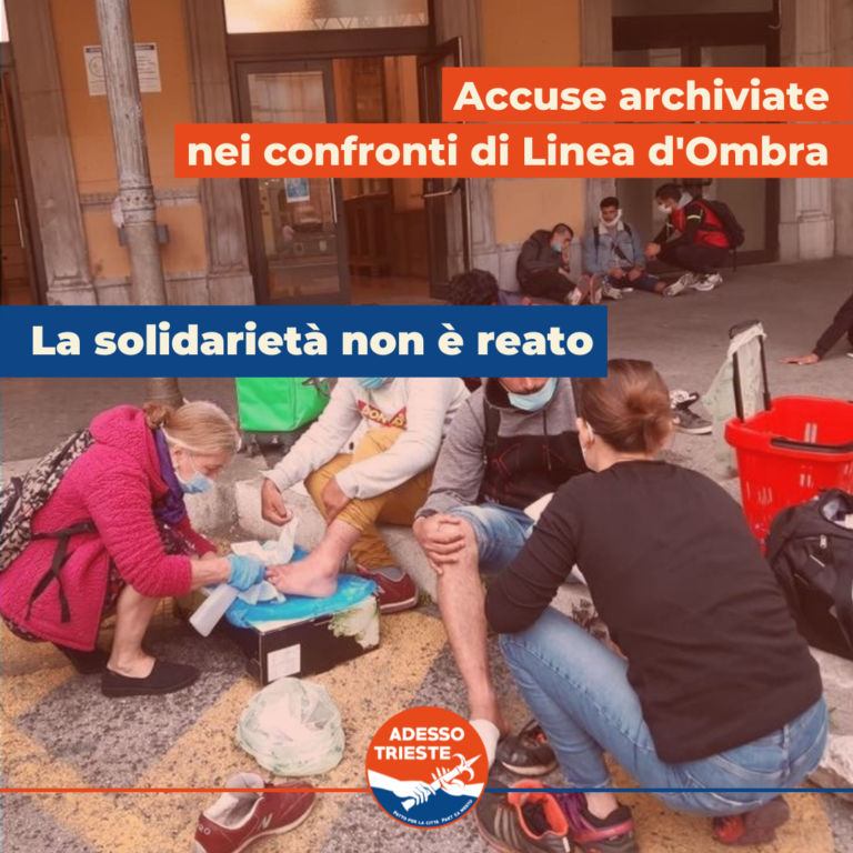 Volontari assistono una persona in strada, con slogan: “La solidarietà non è reato”.