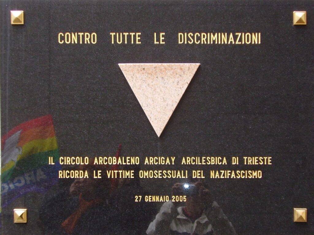 Targa LGBTQ+ Trieste contro le discriminazioni, con triangolo rosa e memoria del nazifascismo.