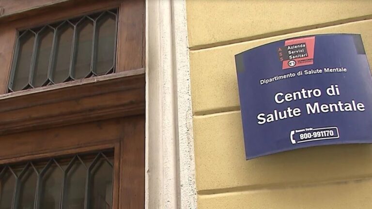 Cartello blu del Centro di Salute Mentale su facciata gialla con inferriata.