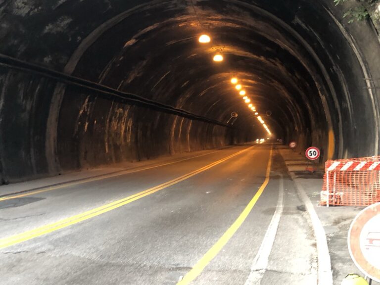 Tunnel di Montebello con strada vuota, luci arancioni e limite 50 km/h.