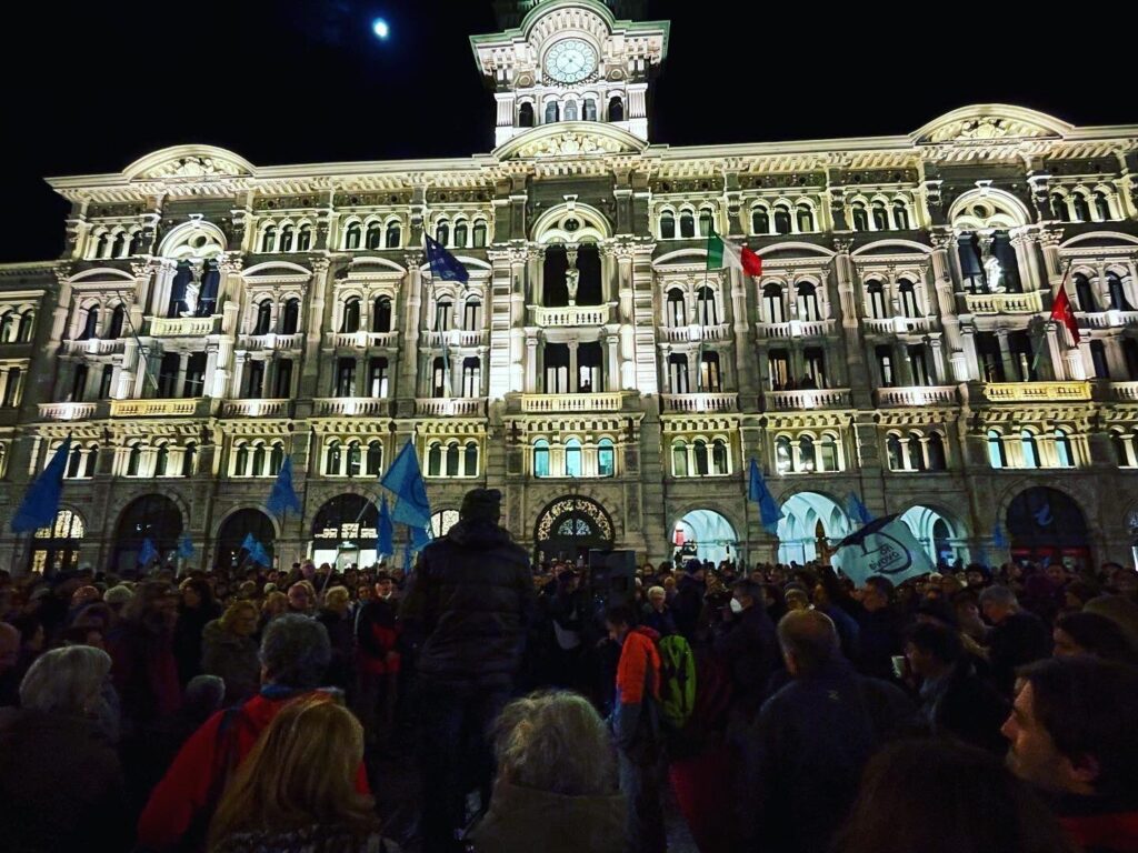Folla notturna davanti a un palazzo storico illuminato durante una celebrazione pubblica.