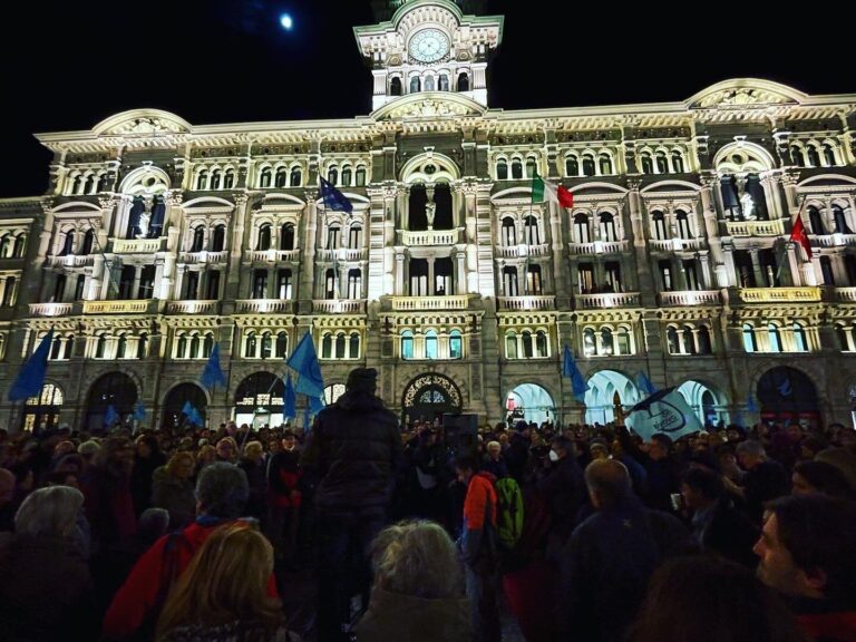 Folla notturna davanti a un palazzo storico illuminato durante una celebrazione pubblica.