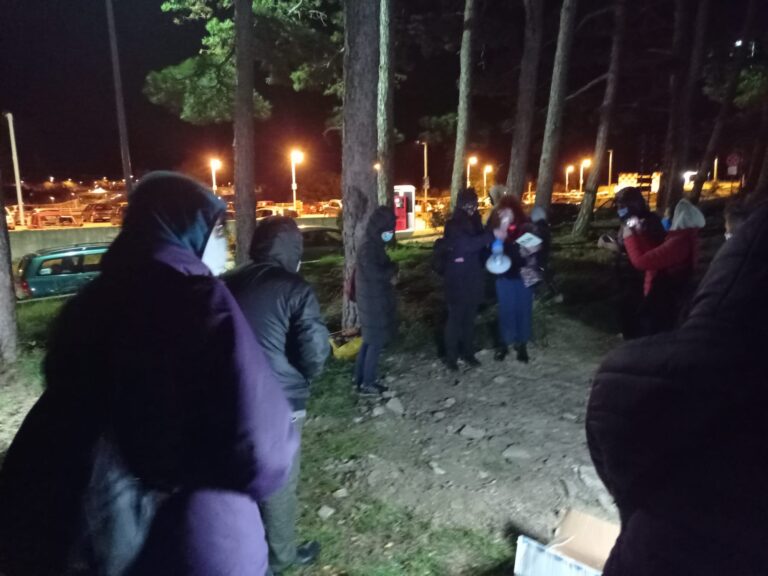 Gruppo nel bosco di notte, con luci artificiali sullo sfondo.