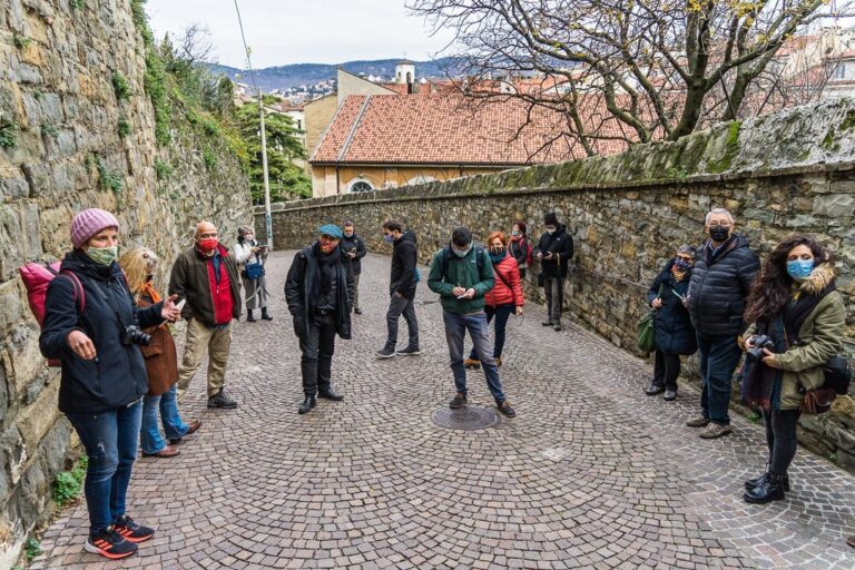 Gruppo in passeggiata guidata su vicolo acciottolato di borgo antico.