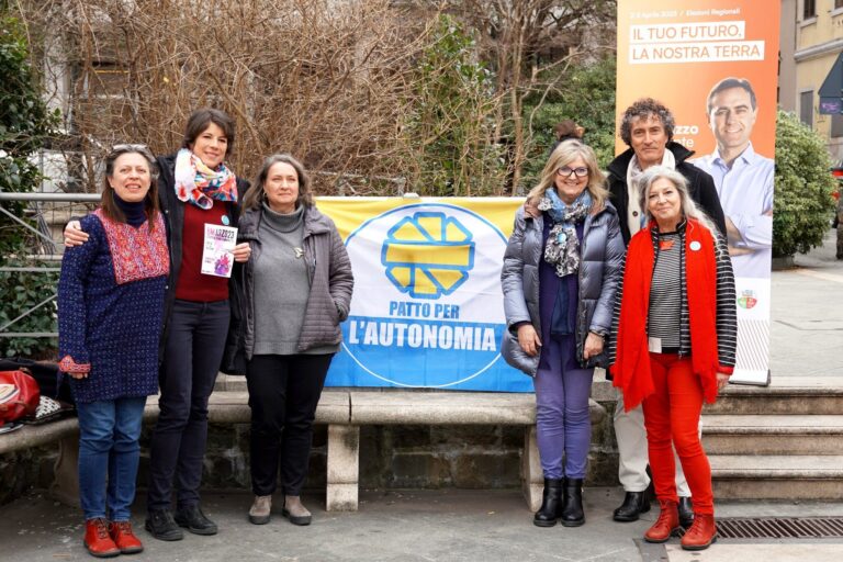 Raduno del Partito dell’Autonomia in piazza con cartello blu e giallo.