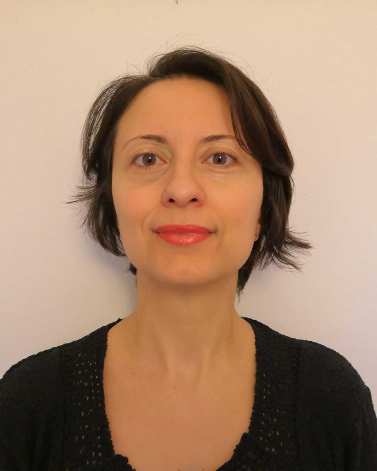Ritratto frontale con capelli corti scuri e top nero su sfondo chiaro.