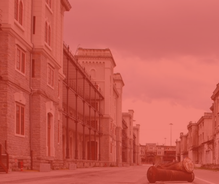 Strada storica rossa con edifici classici, impalcature e cielo nuvoloso.