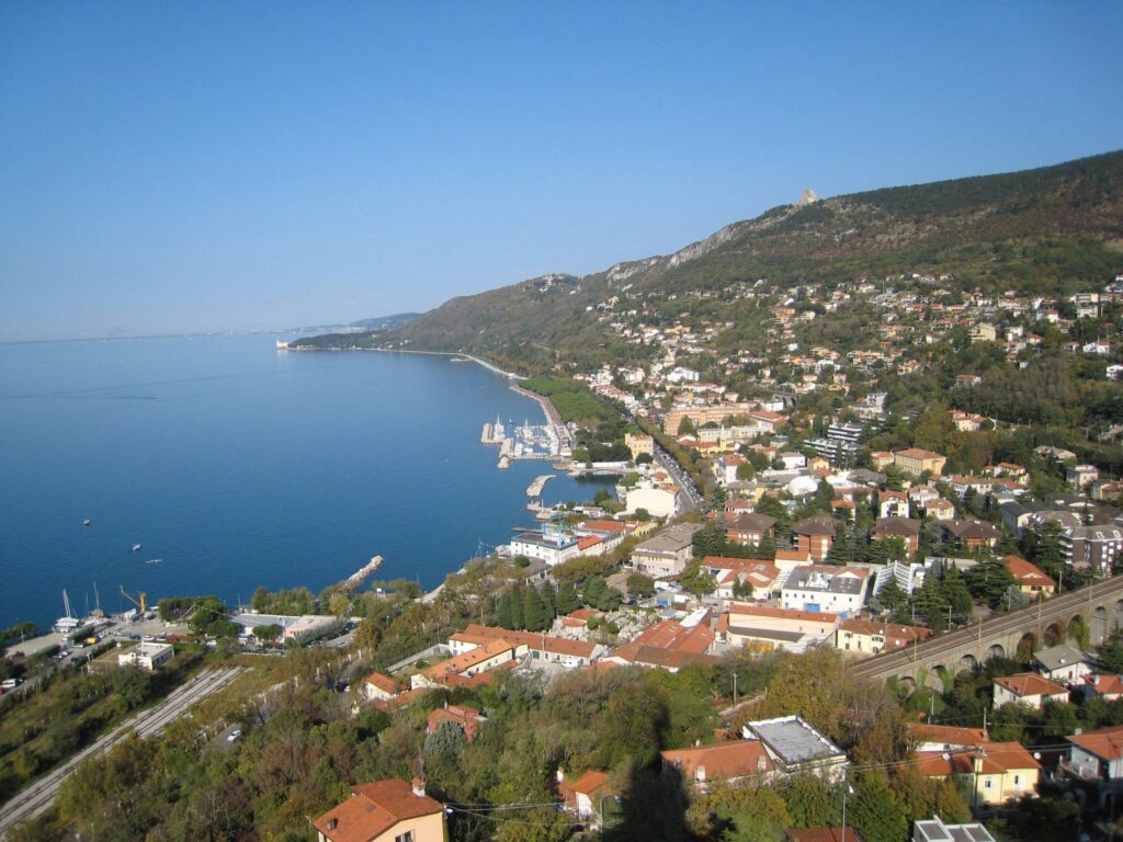 Trieste, baia azzurra, case sul colle e mare Adriatico limpido.