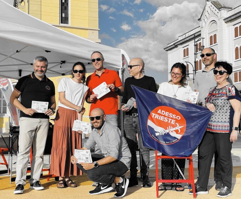 Gruppo Adesso Trieste! in piazza con stand promozionale e cartello “ADESSO TRIESTE!”.
