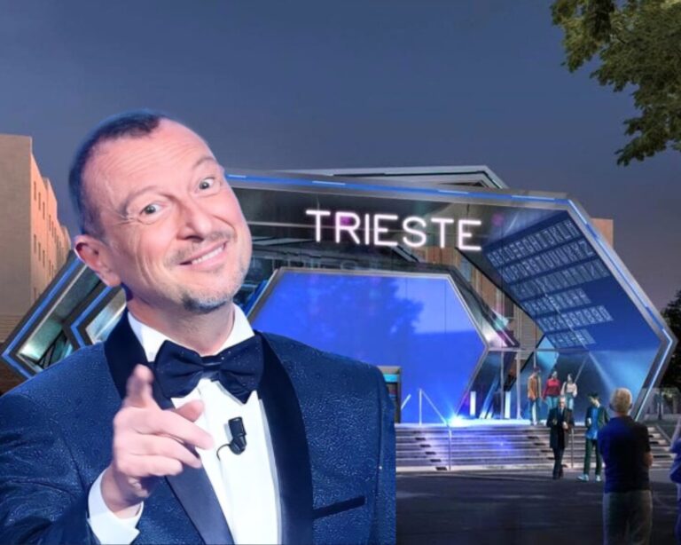 Uomo in smoking sorride e indica Trieste di notte, con palco illuminato sullo sfondo.