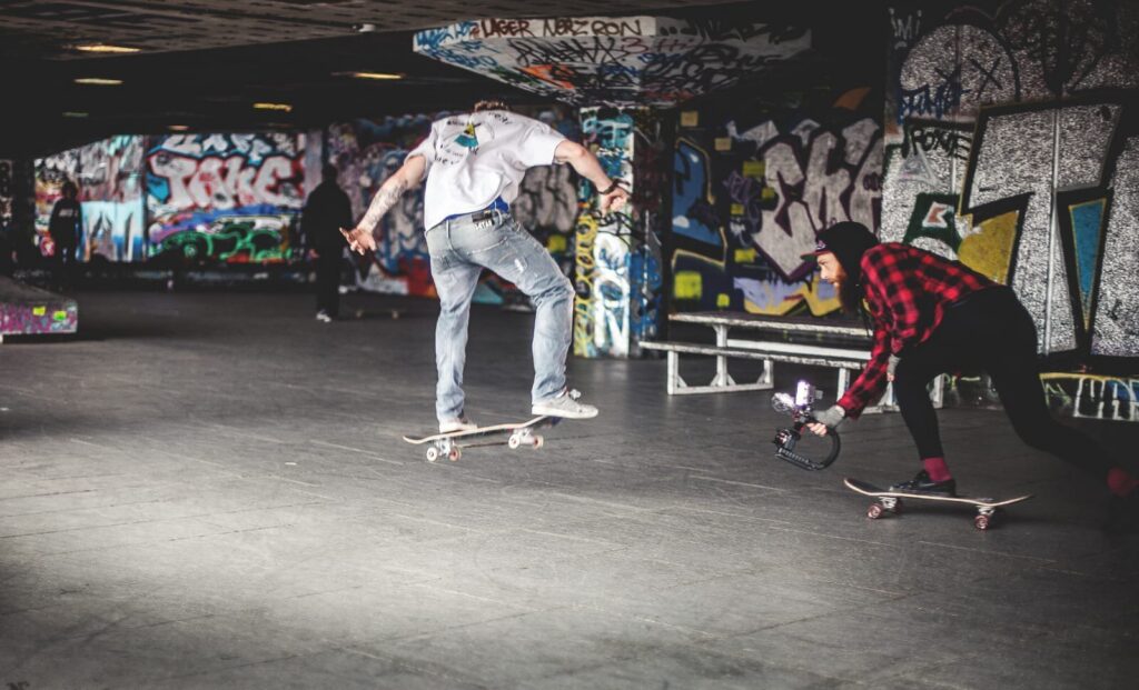 Skateboarder in sottopasso graffiti, due trick street style in scena urbana underground.