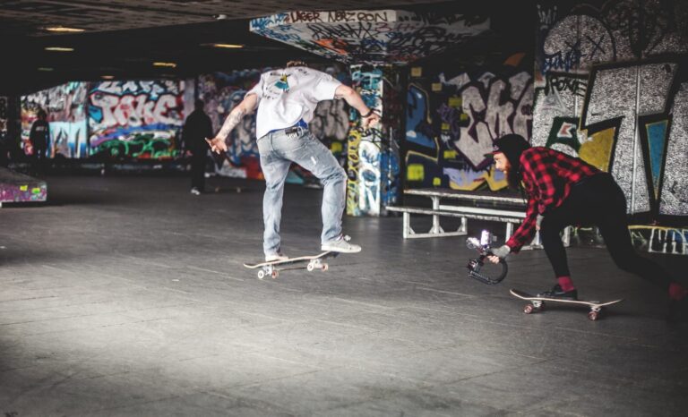 Skateboarder in sottopasso graffiti, due trick street style in scena urbana underground.