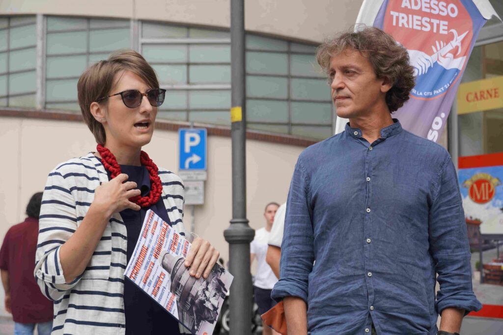 Donna con badge e uomo in camicia blu conversano in strada urbana.