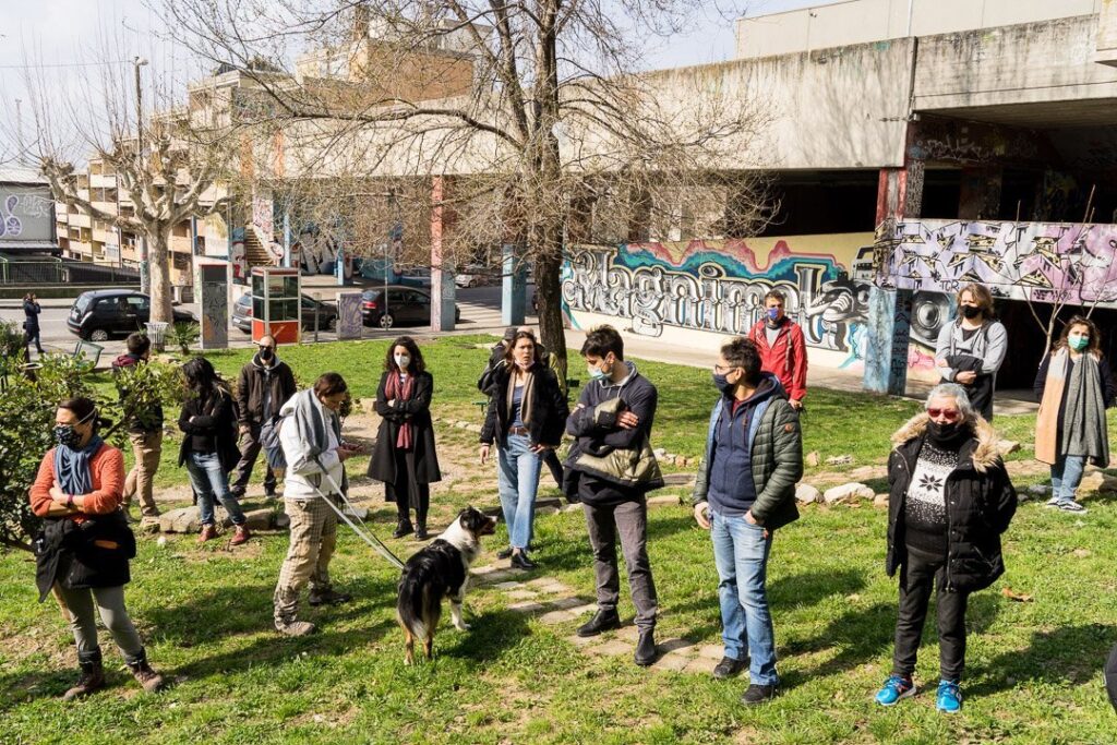 Passeggiata urbana con gruppo, cane e graffiti sotto un ponte nel parco.