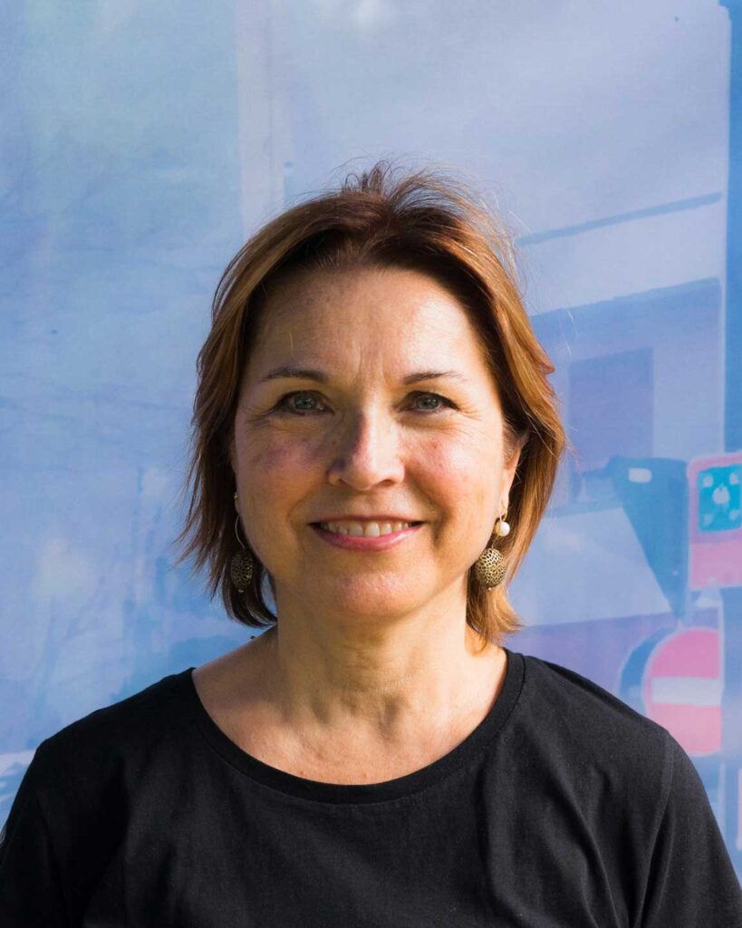 Ritratto professionale di donna sorridente con capelli castani e maglia nera.